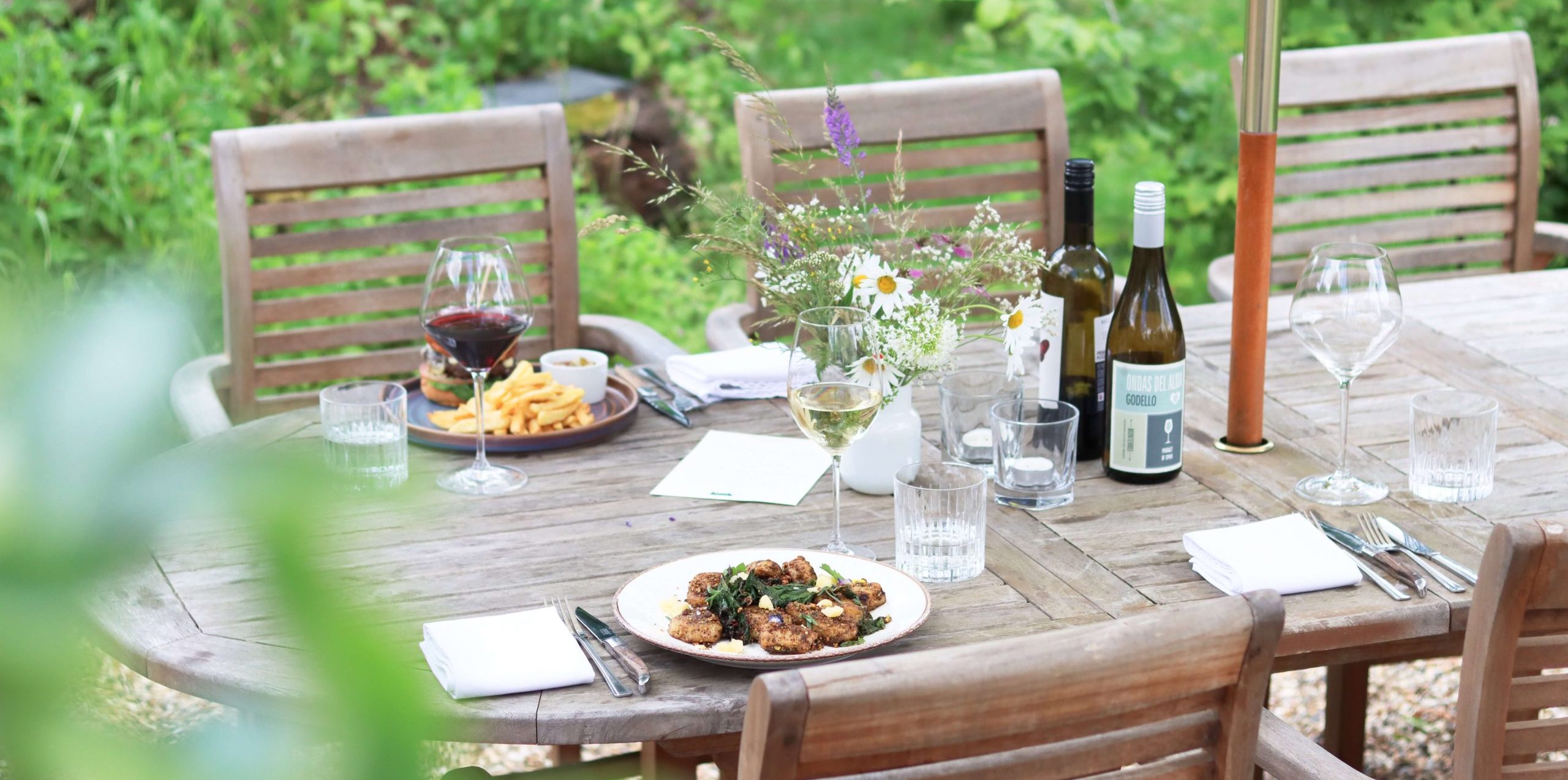 Garden table outdoor dining area. Featuring wine, lunch service set up and food at The Bull Freehouse Pub in Suffolk.